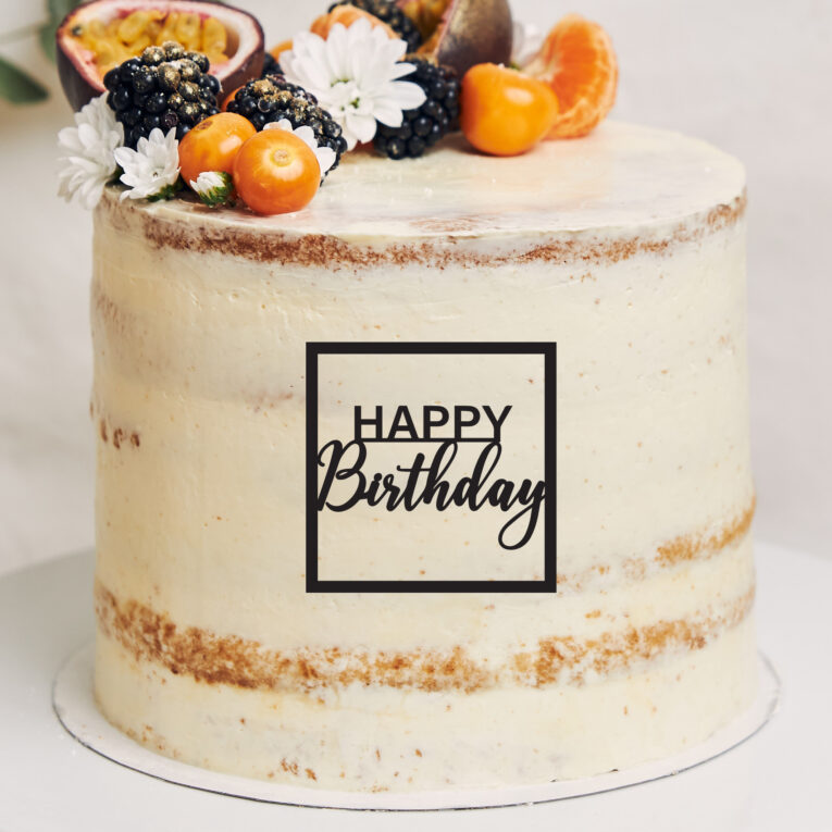 White cake with berries and passionfruits next to a plant behind a white background