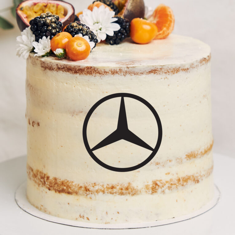 White cake with berries and passionfruits next to a plant behind a white background